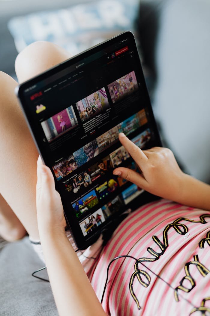 Young girl using a digital tablet indoors, browsing media content during leisure time.